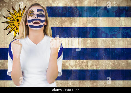 Aufgeregt Ventilator in Uruguay Gesicht Farbe Jubel gegen Uruguay Flagge im grunge Effekt Stockfoto