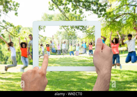 Hand, tablet pc, fröhliche Freunde springen Stockfoto
