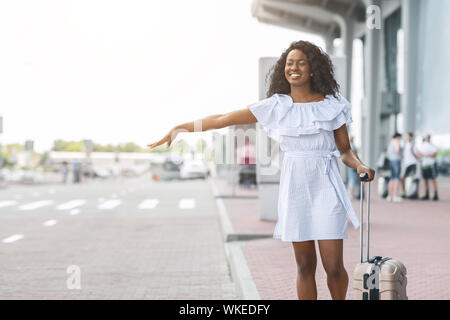 Junge afrikanische Frau, die in der Nähe von Flughafen und versuchen Auto zu stoppen Stockfoto