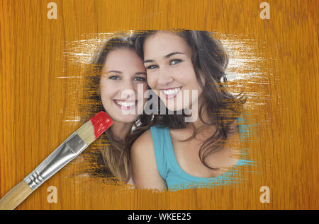 Das zusammengesetzte Bild von Freunden an Kamera lächelnd mit Pinsel in Rot getaucht gegen Holz Kiefer Tisch Stockfoto