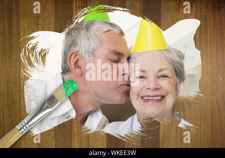 Das zusammengesetzte Bild im Senior Paar feiert Geburtstag mit Pinsel eingetaucht in Grün vor Holz- Oberfläche mit Planken Stockfoto