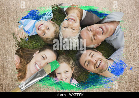 Das zusammengesetzte Bild der erweiterten Familie lächelnd an Kamera mit Pinsel eingetaucht in Grün gegen die verwitterte Oberfläche Stockfoto