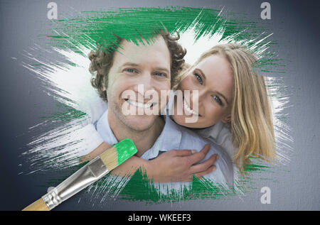 Das zusammengesetzte Bild im Paar in die Kamera lächelnd mit Pinsel eingetaucht in Grün vor digital erzeugten Grau vignette Hintergrund Stockfoto