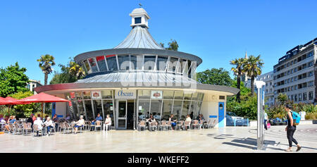 Touristen und Käufer sitzen draußen in der Sonne zu Obscura Street Cafe im Stadtzentrum das Quadrat in Bournemouth Badeort Dorset England UK Stockfoto