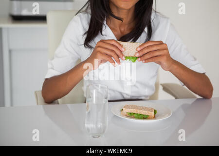 Hübsche Geschäftsfrau essen ein Sandwich an Ihrem Schreibtisch in Ihrem Büro Stockfoto