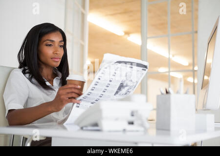 Hübsche Geschäftsfrau lesen Zeitung an Ihrem Schreibtisch in Ihrem Büro Stockfoto
