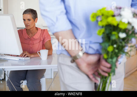 Geschäftsmann ausblenden Blumen hinter zurück für die Kollegen im Büro Stockfoto
