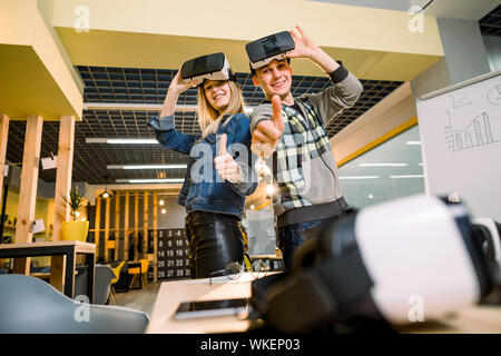 Begeistert junge schöne Paar Tests Virtual Reality 3D-Brille VR-Headset im casual Outfit durch Augmented Reality neugierig modern gekleidet Stockfoto