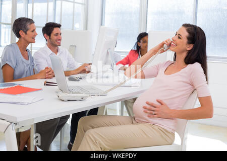 Geschäftsfrau am Telefon und Anschläge preganat Bauch im Büro Stockfoto