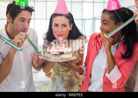 Geschäftsfrau ausblasen Kerzen auf Kuchen im Büro Stockfoto