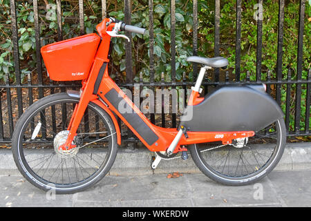 Orange Farbe Springen mieten Fahrräder von Uber ein batteriebetriebenes GPS app Tracker electric Pedal assist Fahrrad neben Geländer London England UK geparkt Stockfoto