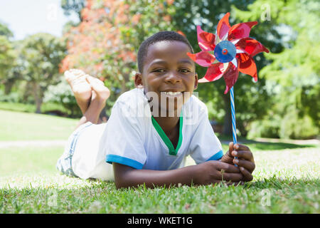 Little Boy holding Windrad im Park an der Kamera lächelnd an einem sonnigen Tag Stockfoto