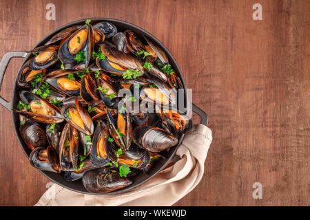 Marinara Muscheln, Moules Mariniere, in einem großen Topf kochen, Overhead shot auf einem dunklen Holzmöbeln im Landhausstil Hintergrund Stockfoto