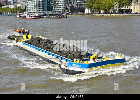 Themse lange Lastkahn & Last des Bodens von der Konstruktion der Themse Tideway Tunnel Abwasserkanal Projekt nach unten gedrückt wird, um den Fluss von Tug Boat London England Großbritannien Stockfoto