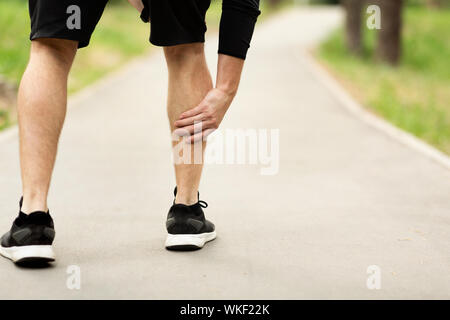 Männliche Läufer leidet an der Wade Schmerzen beim Joggen Stockfoto