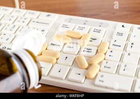 Pillen auf Tastatur Computer auf hölzernen Hintergrund Konzept Technologie sucht Stockfoto