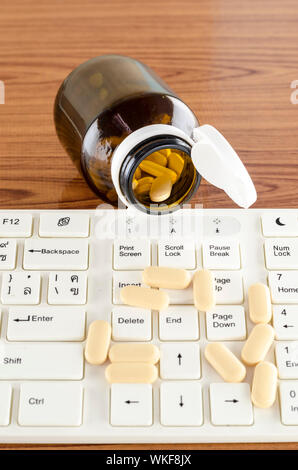 Pillen auf Tastatur Computer auf hölzernen Hintergrund Konzept Technologie sucht Stockfoto