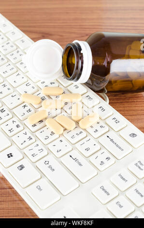 Pillen auf Tastatur Computer auf hölzernen Hintergrund Konzept Technologie sucht Stockfoto