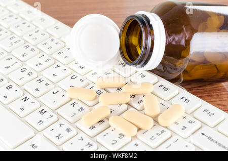 Pillen auf Tastatur Computer auf hölzernen Hintergrund Konzept Technologie sucht Stockfoto