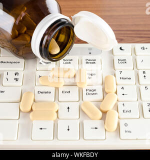 Pillen auf Tastatur Computer auf hölzernen Hintergrund Konzept Technologie sucht Stockfoto