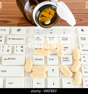 Pillen auf Tastatur Computer auf hölzernen Hintergrund Konzept Technologie sucht Stockfoto