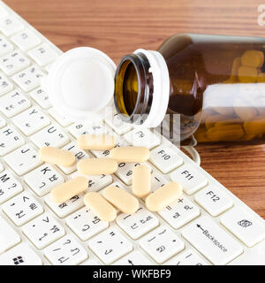 Pillen auf Tastatur Computer auf hölzernen Hintergrund Konzept Technologie sucht Stockfoto