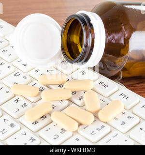 Pillen auf Tastatur Computer auf hölzernen Hintergrund Konzept Technologie sucht Stockfoto