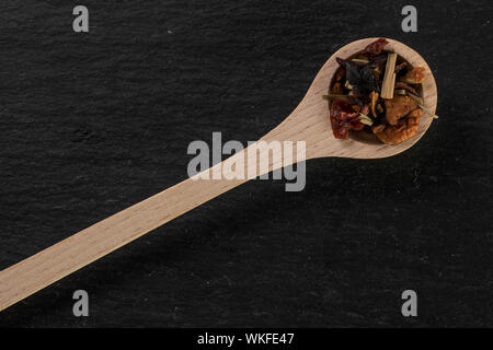 Viele Stücke von preiselbeere Erdbeere Früchtetee mit Holzlöffel flatlay am grauen Stein Stockfoto