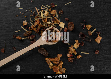 Viele Stücke von preiselbeere Erdbeere Früchtetee mit Holzlöffel flatlay am grauen Stein Stockfoto