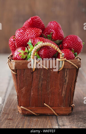 Frische reife Erdbeeren in vintage Warenkorb auf einer hölzernen Hintergrund Stockfoto