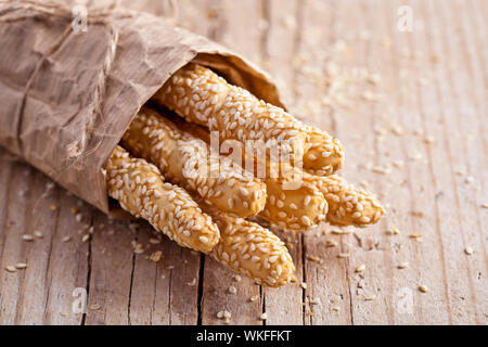 Brot sticks Grissini mit Sesam in craft Pack auf rustikalen Holzmöbeln Hintergrund Stockfoto