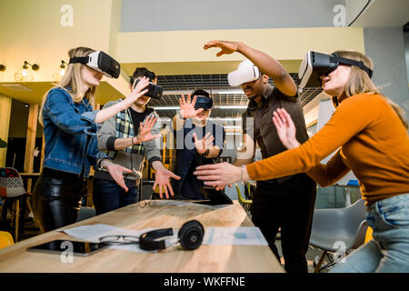Junge multirassischen Business Leute mit Virtual reality Brillen mit berühren Luft während der VR-Konferenz Konferenz im Büro. Business Männer und Frauen Stockfoto