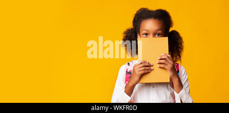 Afrikanische amerikanische Schülerin für Gesicht mit Buch, Gelber Hintergrund Stockfoto