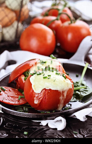 Eier mit Mozzarella mit frischen Tomaten gebacken und garniert mit Schnittlauch. Extrem geringe Tiefenschärfe. Stockfoto