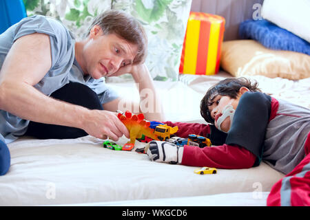 Schönen Vater spielen Autos mit behinderten Sohn auf Bodenmatte Stockfoto