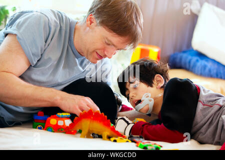 Schönen Vater spielen Autos mit behinderten Sohn auf Bodenmatte Stockfoto