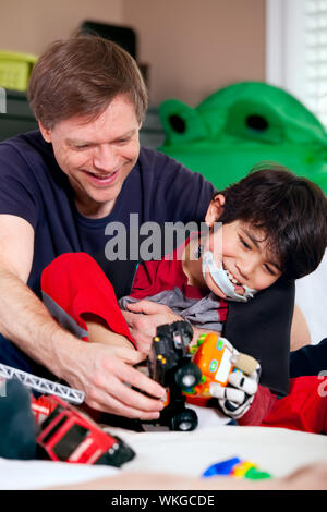 Schönen Vater spielen Autos mit behinderten Sohn auf Bodenmatte Stockfoto