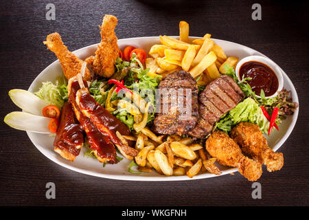 Gesunde platter gemischter Aufschnitt einschließlich gegrilltes Steak, knusprig panierte Hähnchen und Rindfleisch auf einem Bett von frischem grünem Salat serviert mit Französischen Stockfoto