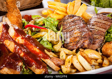 Platte mit gemischtem Fleisch, Salat und Pommes frites Stockfoto
