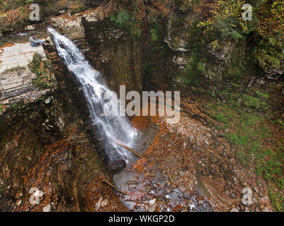 Mann, der auf einem Felsen am Wasserfall Herbst Zeit suchen Stockfoto
