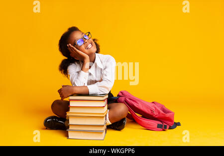 African American Elementary Student Mädchen träumen Sitzen im Stapel buchen Stockfoto