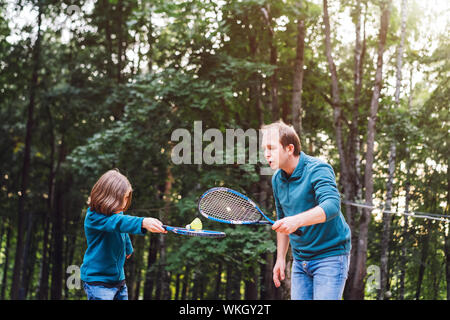 Vater lehrt Sohn Badminton im Park zu spielen. Wochenende für Zwei. Stockfoto