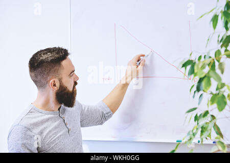 Bärtige hipster, Lehrer oder Schüler zieht Chart auf dem Whiteboard während der Lektion im Klassenzimmer Stockfoto