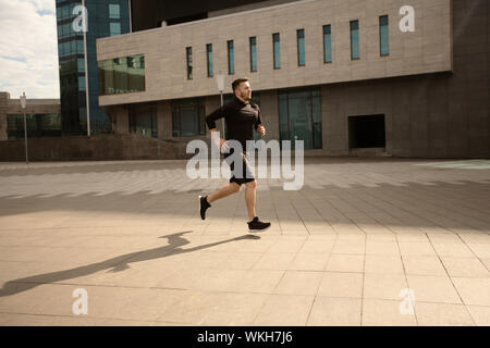 Sportliche Mann laufen im Freien, in cardio Training gegen Stadtbild Stockfoto