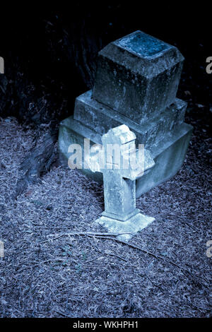 Kleinen Weißen Kreuzes Tombstone in einem ländlichen Friedhof bei Nacht. Stockfoto