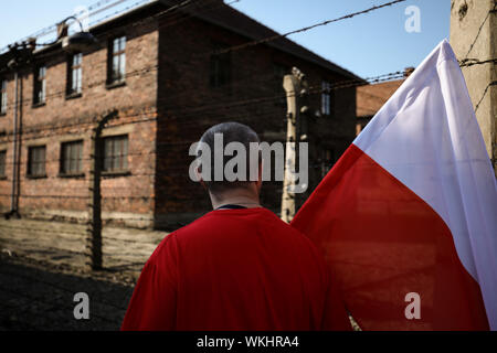 Polen, OSWIECIM-14 August 2019: Der Mann mit der polnischen Flagge, Weiß und Rot, während die Katholiken gegenüber Vernichtungslager Auschwitz-Birkenau entfernt. Stockfoto