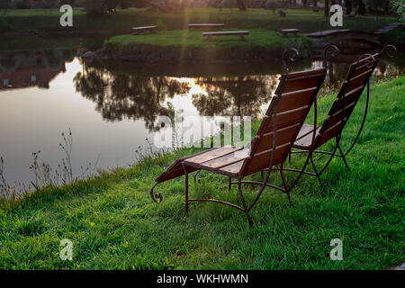 Zone Rest. Hölzerne Stühle stehen auf der Wiese am See, mit Blick auf den See. Weißrussland Stockfoto