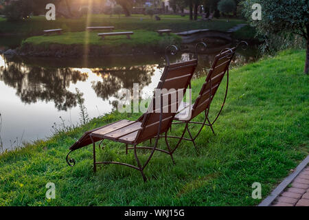 Zone Rest. Hölzerne Stühle stehen auf der Wiese am See, mit Blick auf den See. Weißrussland Stockfoto