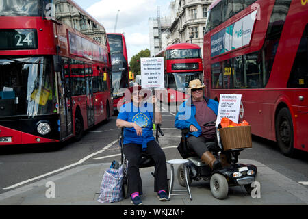 4. September 2019 das Parlament. Zwei ältere bleiben Demonstranten mit Behinderungen Protest auf der Verkehrsinsel vor dem Parlament. Stockfoto