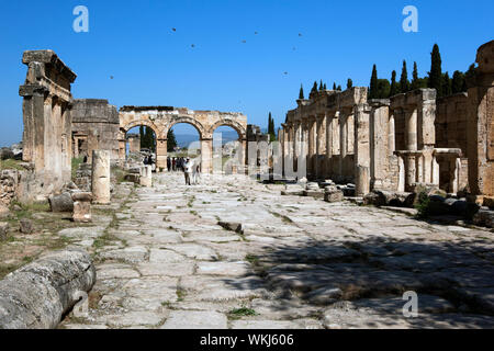 Die Ruinen von Kriegslisten des Frontinus Straße mit Blick auf den Arch von Domitian in der antiken Stadt Hierapolis in der Nähe von Pamukkale in der Türkei entfernt. Stockfoto